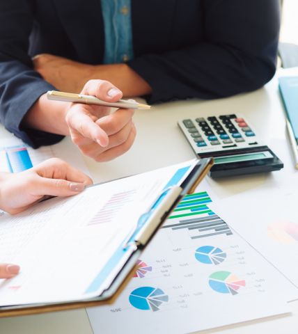 Análisis de gráficos financieros con calculadora y documentos sobre la mesa